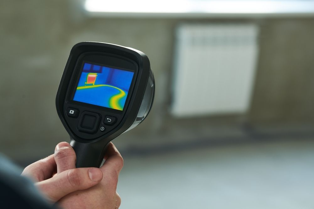 A person is holding a thermal camera in their hand.