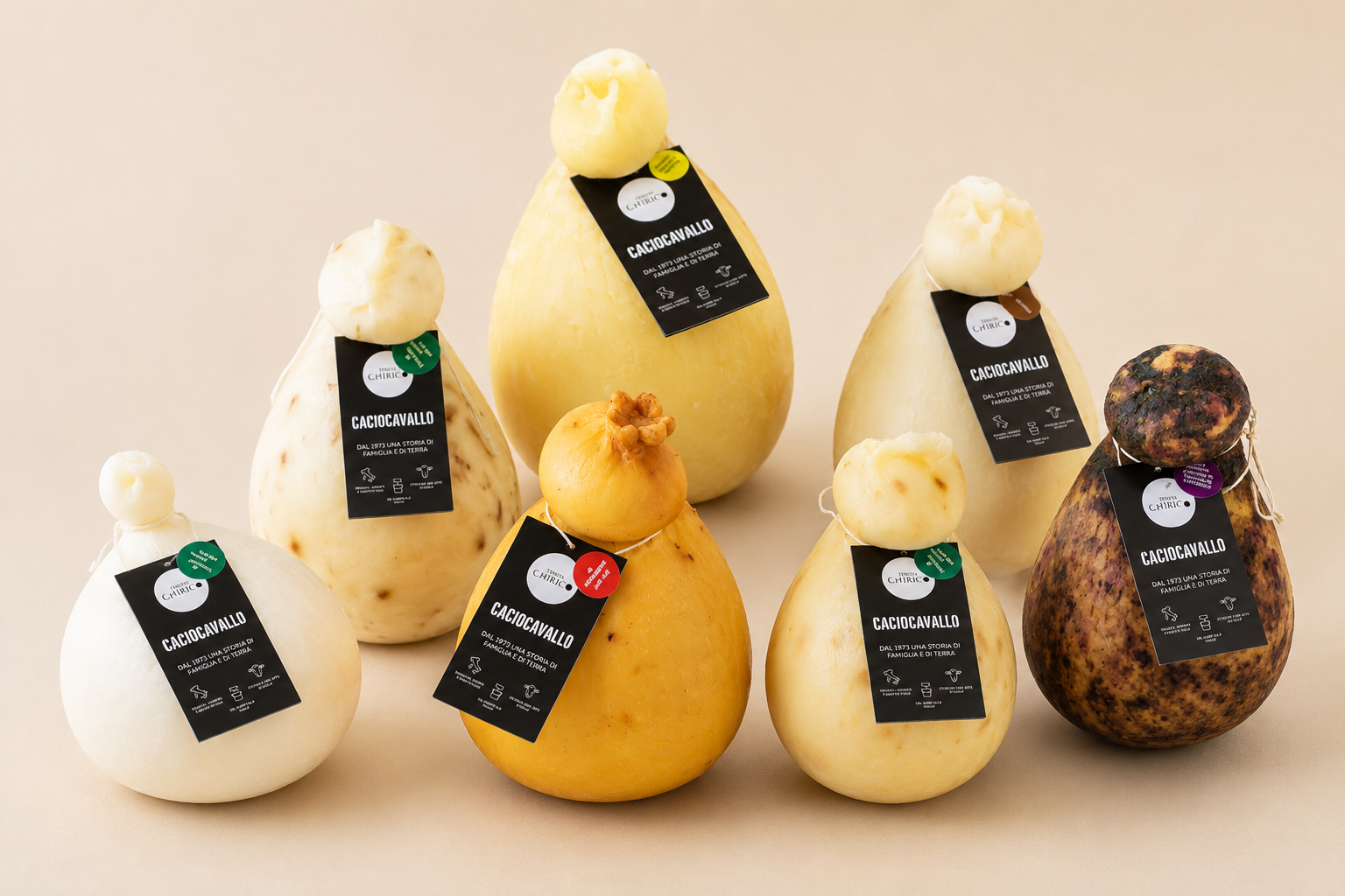 Caciocavalli assortiti  disposti su una superficie beige chiaro.