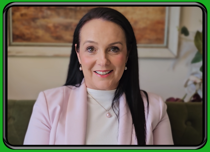Woman in a pink blazer speaking on camera against a bright green background.