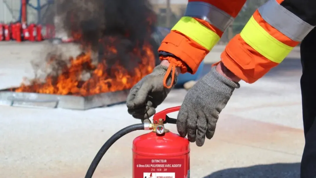 Un pompier utilise un extincteur devant un incendie.