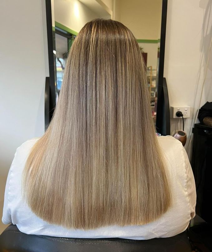 A Woman With Long Blonde Hair is Sitting in a Chair in Front of a Mirror — Choo Choo Hair and Beauty In Wyong, NSW A Woman With Long Blonde Hair is Sitting in a Chair in Front of a Mirror — Elysian Salon In Wyong, NSW