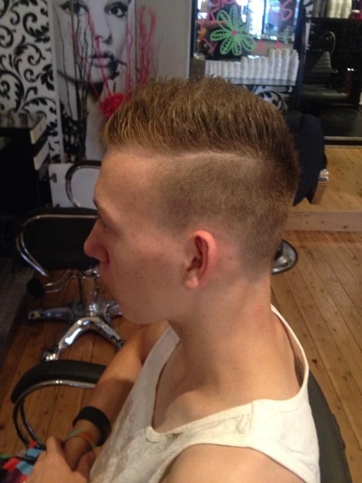 A Man in a White Tank Top is Sitting in a Chair With His Hair Cut — Elysian Salon In Wyong, NSW