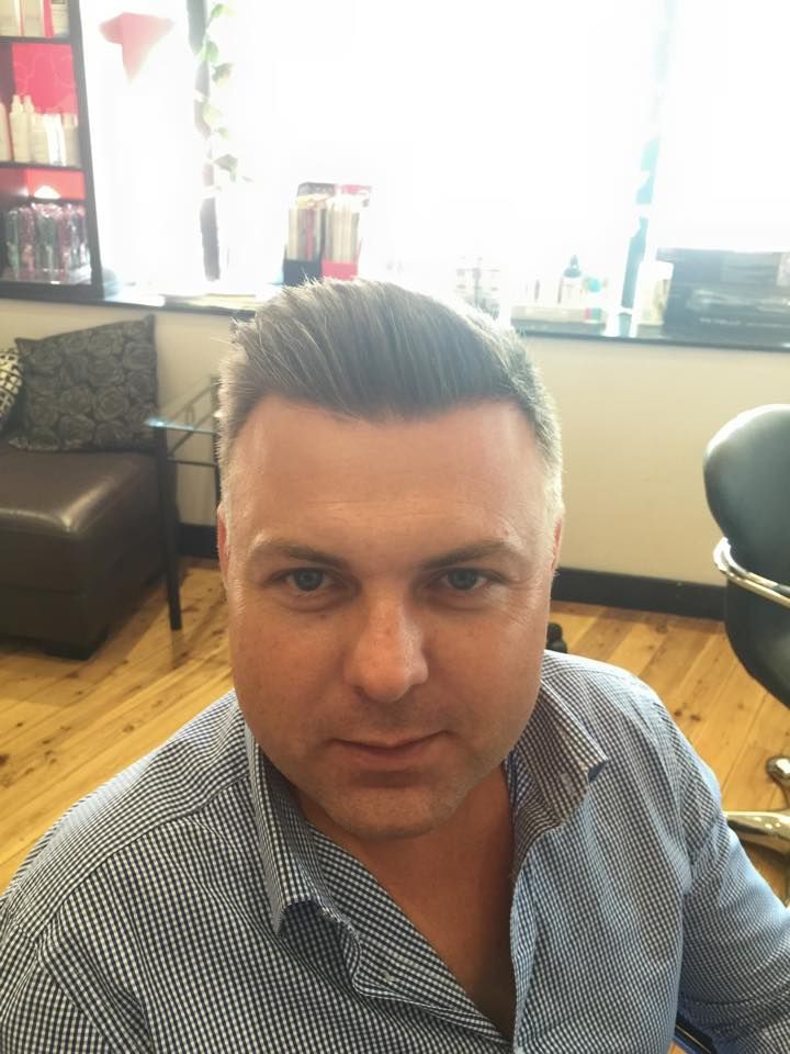 A Man in a Blue Shirt is Sitting in a Chair in a Salon — Elysian Salon In Wyong, NSW