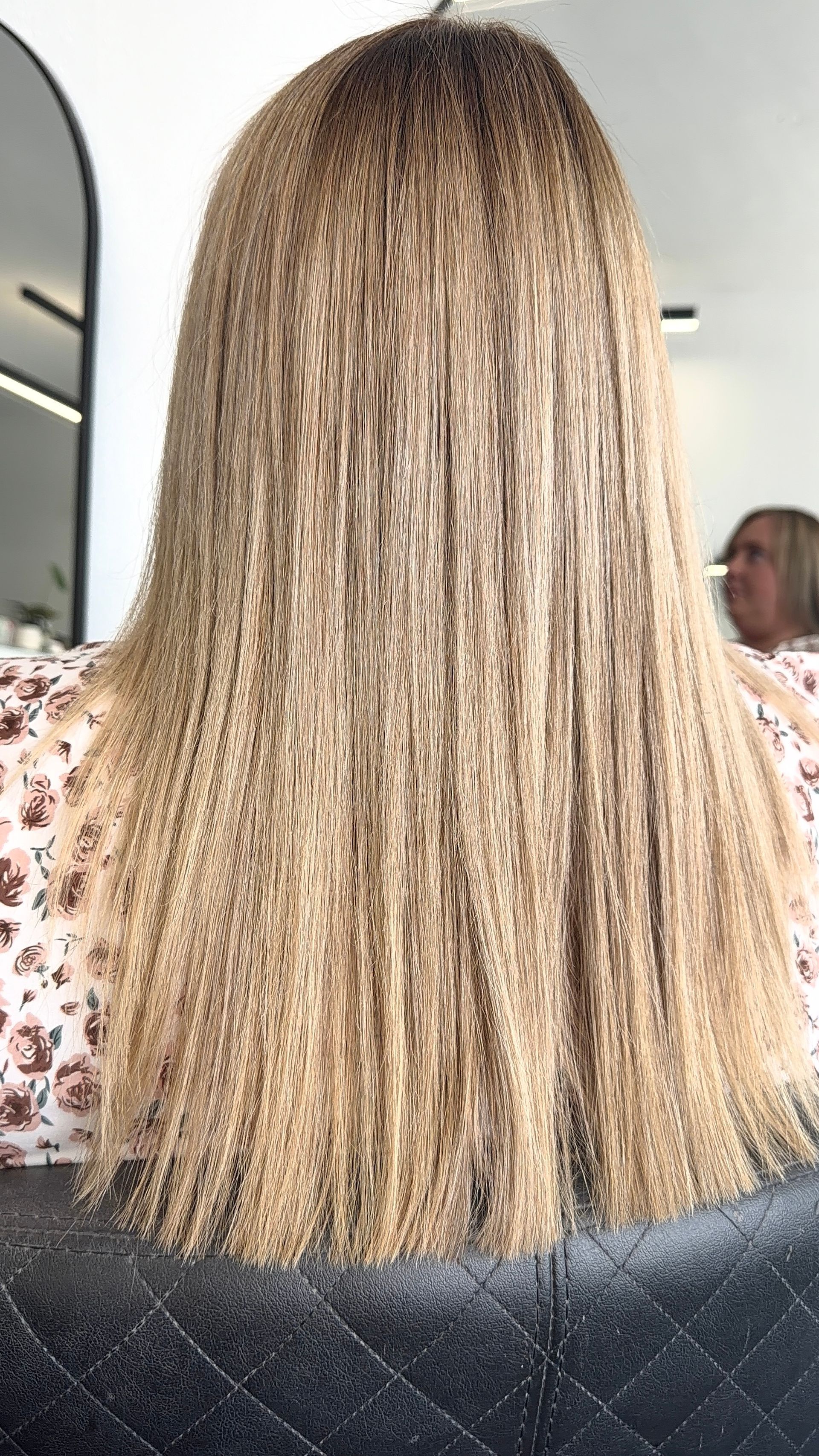 Straight Blonde Hair Viewed From Behind in a Salon Chair, With a Mirror and Another Person — Elysian Salon In Wyong, NSW