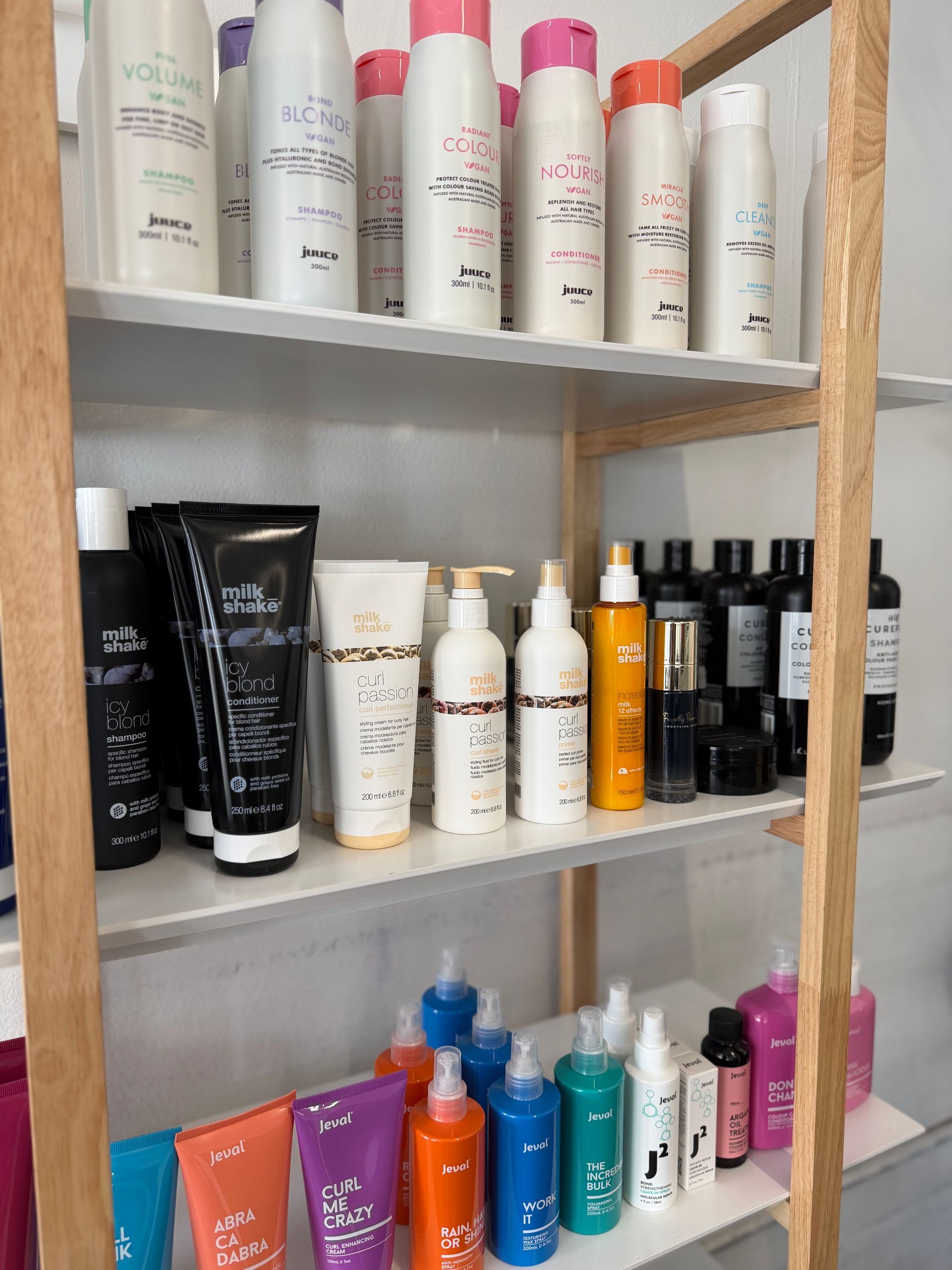 A Woman With Purple and Pink Hair is Sitting in a Chair — Choo Choo Hair and Beauty In Wyong, NSW Shelves of assorted skincare and cosmetic bottles in a bathroom or vanity cabinet — Elysian Salon In Wyong, NSW