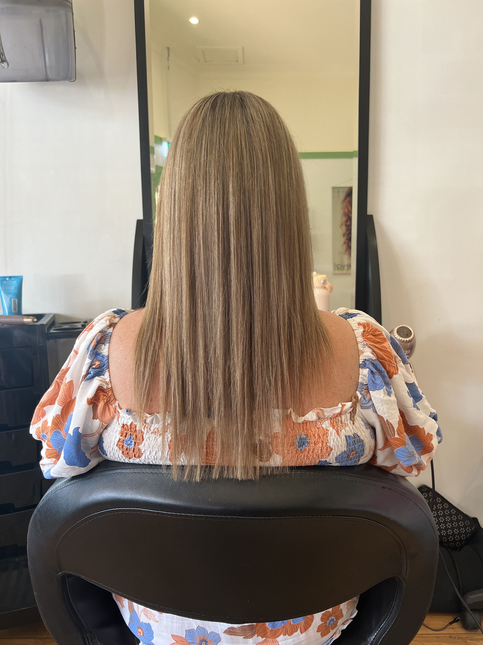 Person Seated in a Chair, Seen From Behind, With Long Curly Hair — Elysian Salon In Wyong, NSW