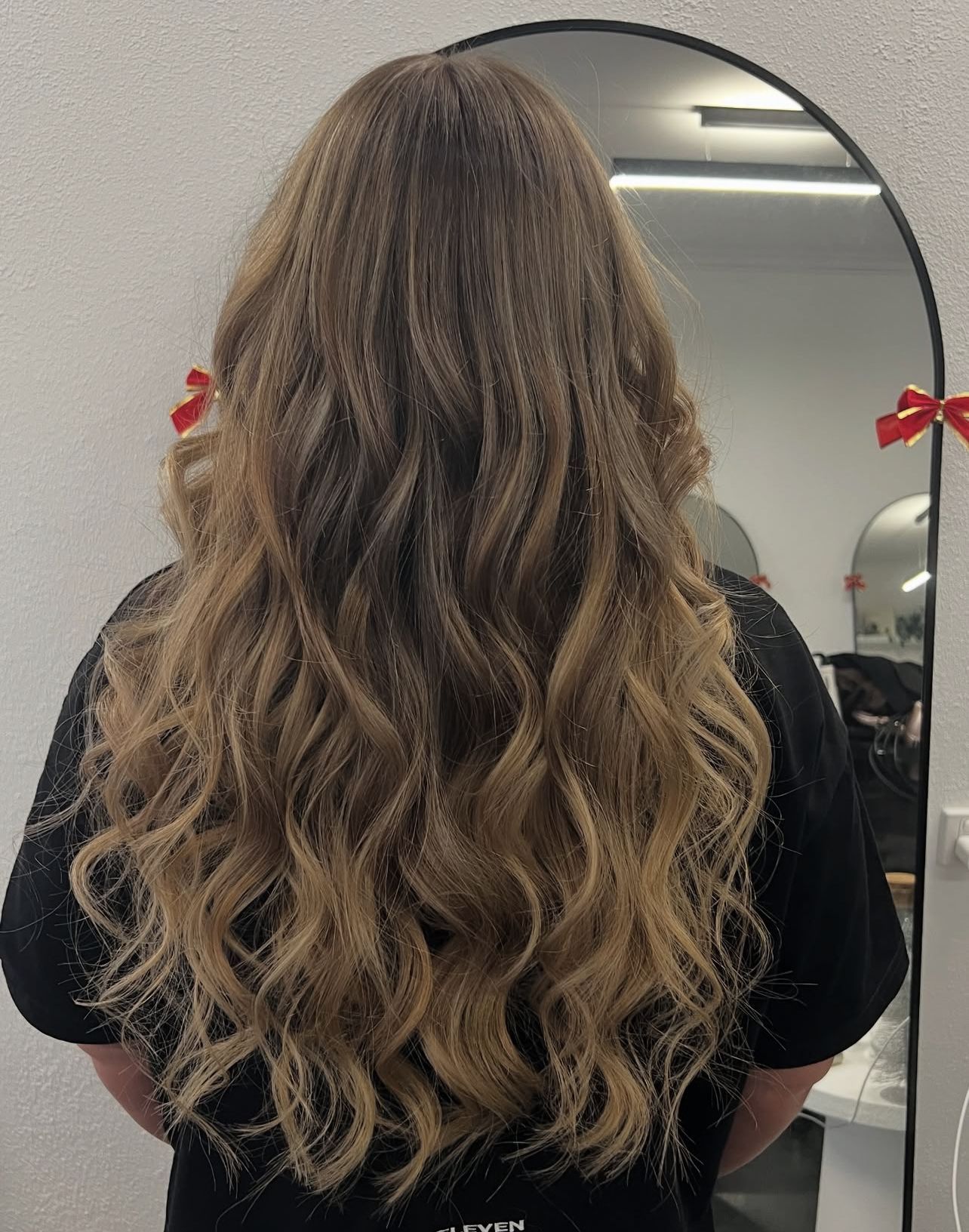 Long wavy blonde-brown hair viewed from behind in a salon mirror area  — Elysian Salon In Wyong, NSW