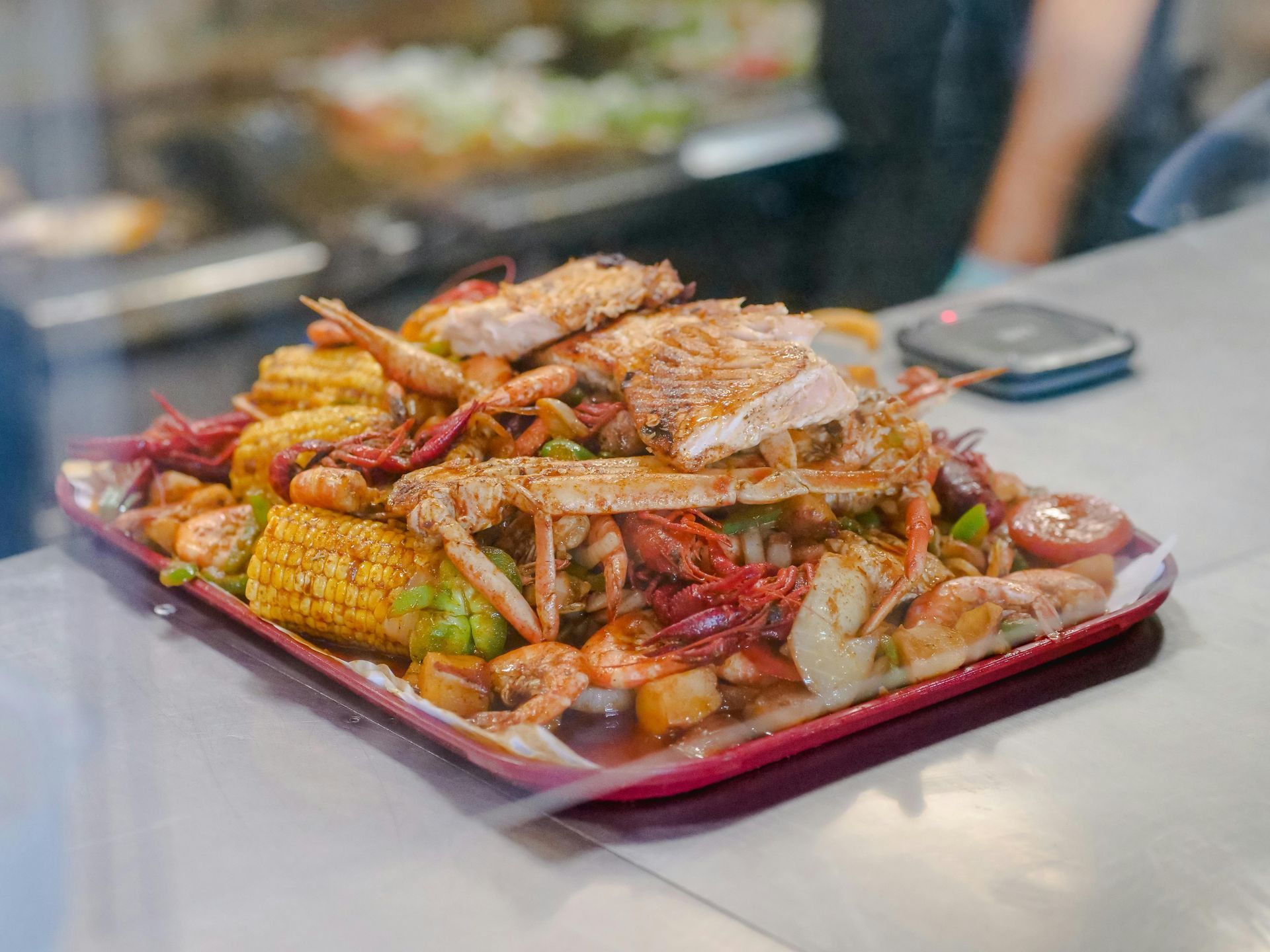 Seafood boil: crab, shrimp, crawfish, corn, potatoes, sausage, with seasoning, on a platter.