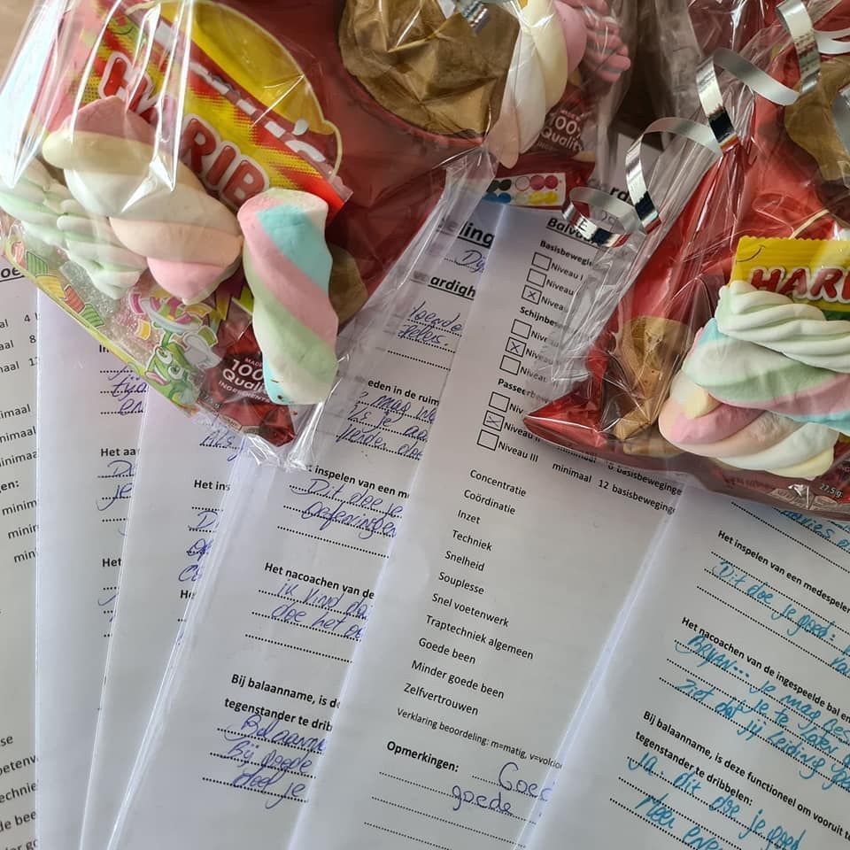 Doorzichtige plastic zakjes gevuld met pastelkleurige snoepjes liggen over geprinte documenten op een bureau.