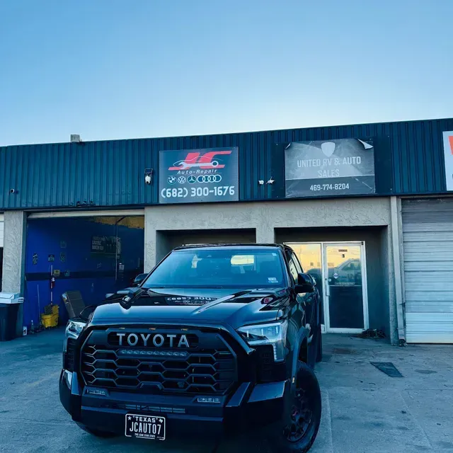 Black Toyota truck parked outside an auto shop with blue and gray garage doors. | JC Auto Repair LLC