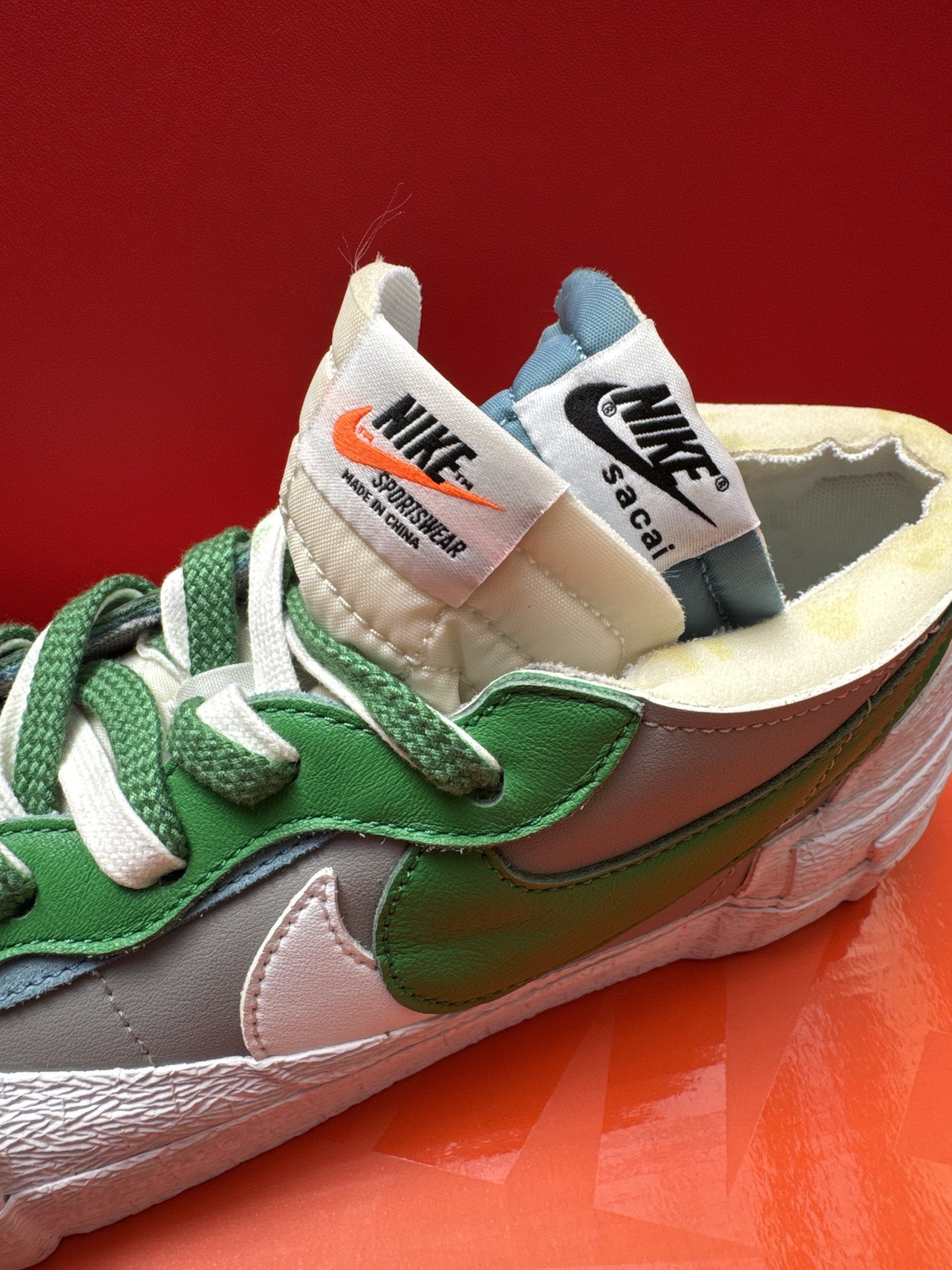 Nike Blazer Low shoes, gray and green, on a red box with an orange background.
