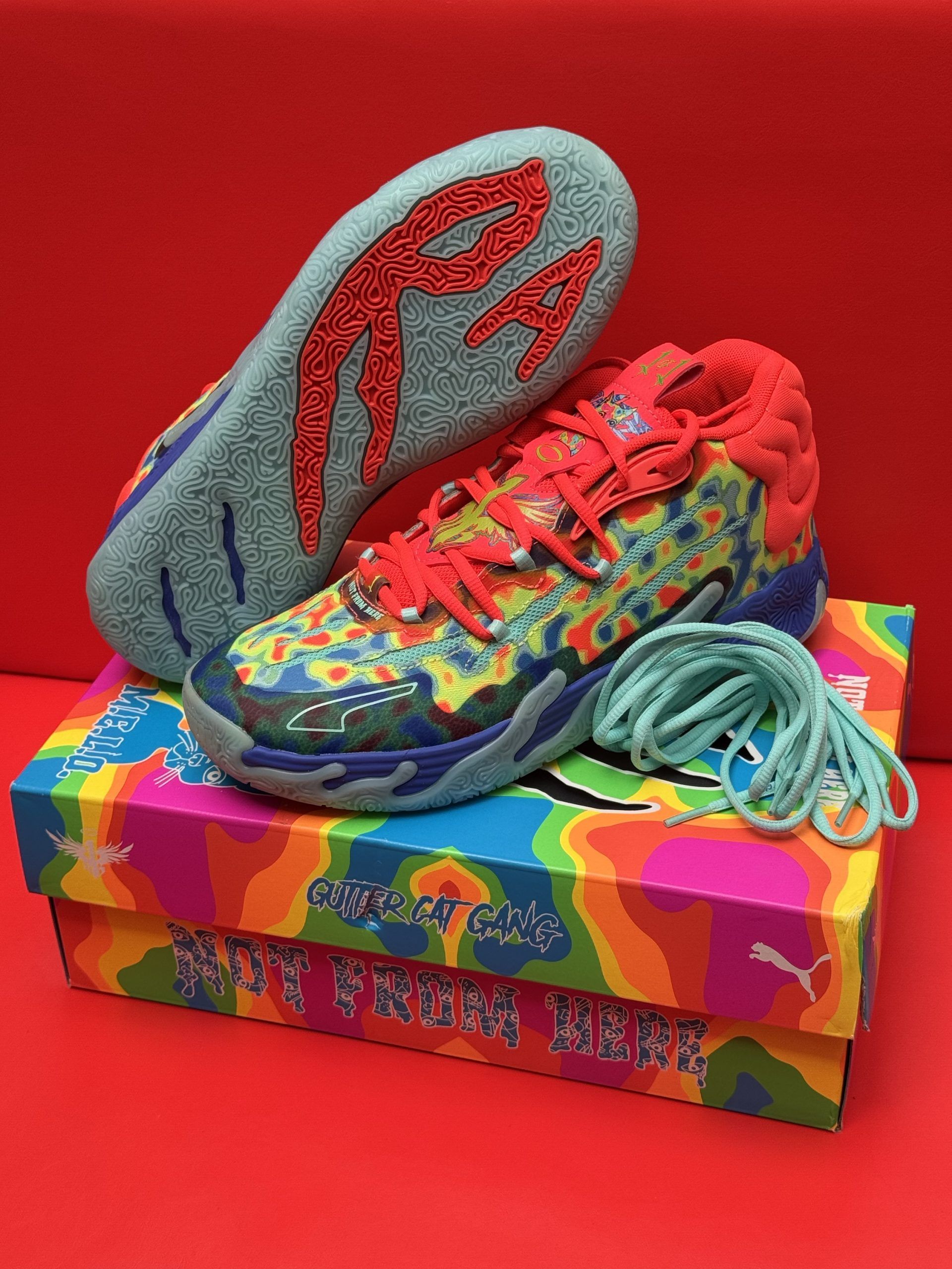 Colorful Puma basketball shoes with matching box and laces against a red backdrop.