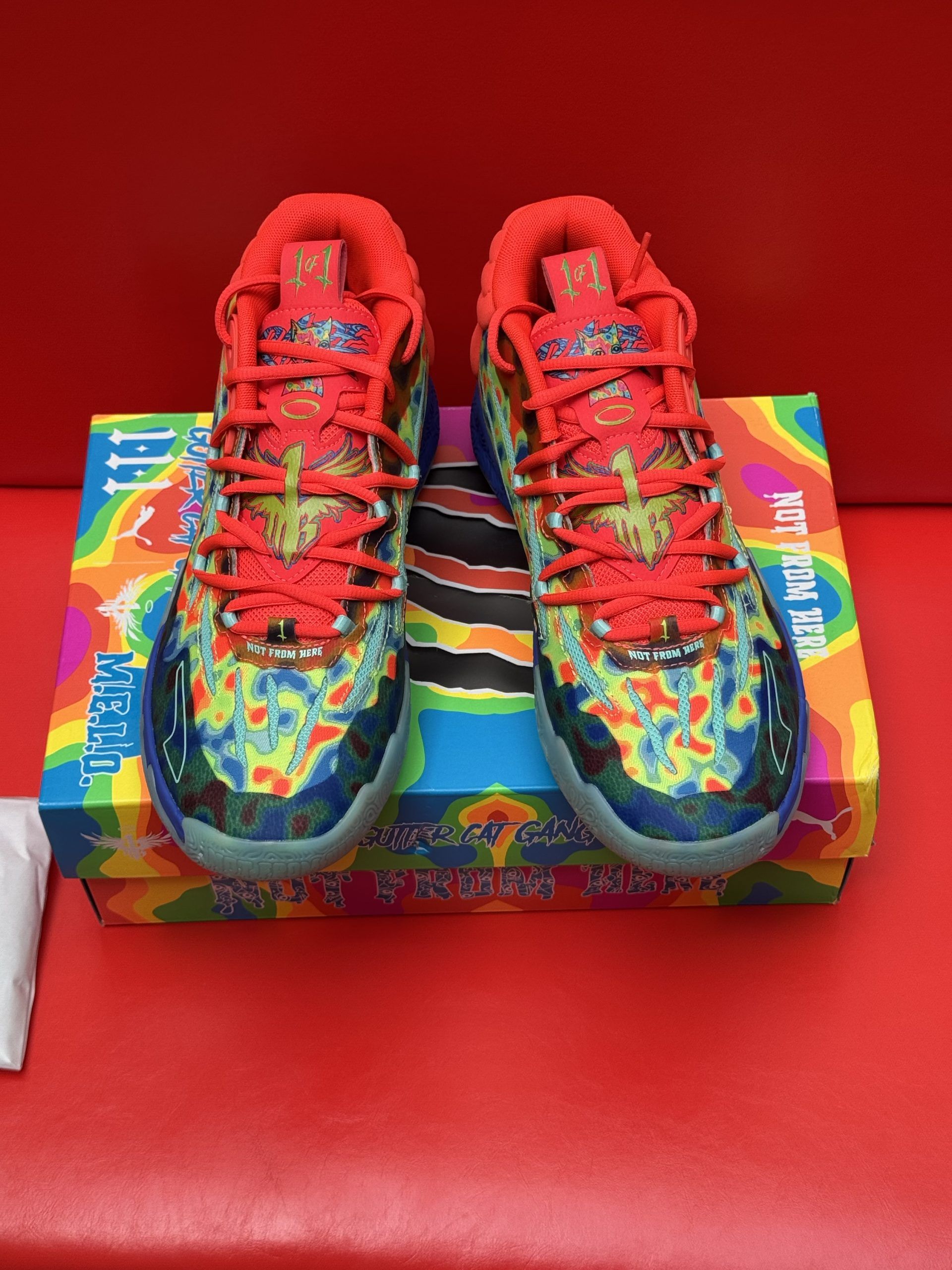 Colorful Puma basketball shoes with matching box and laces against a red backdrop.