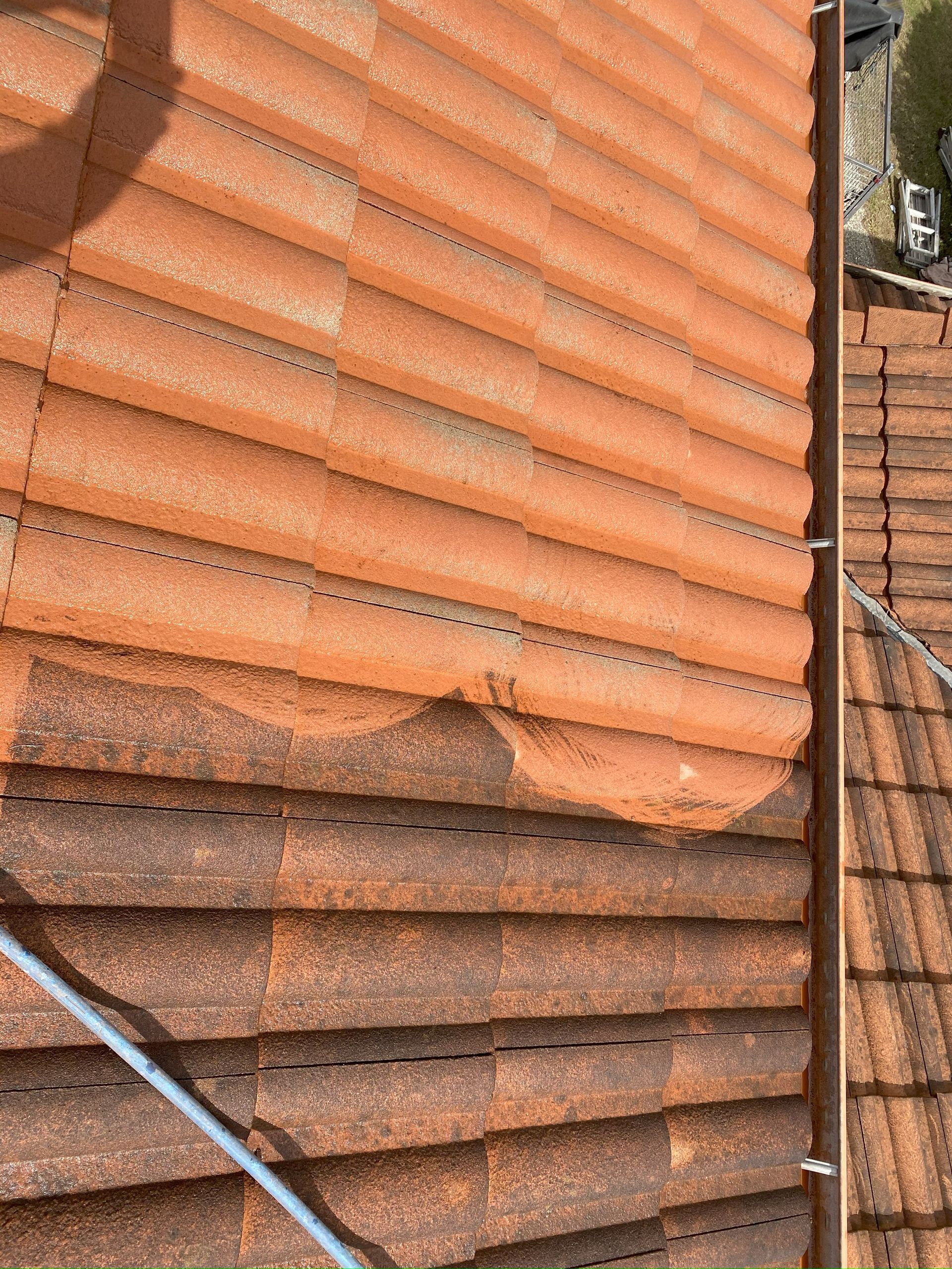 Terracotta roof tiles; lower section appears cleaned, showing a visible contrast in color and cleanliness.