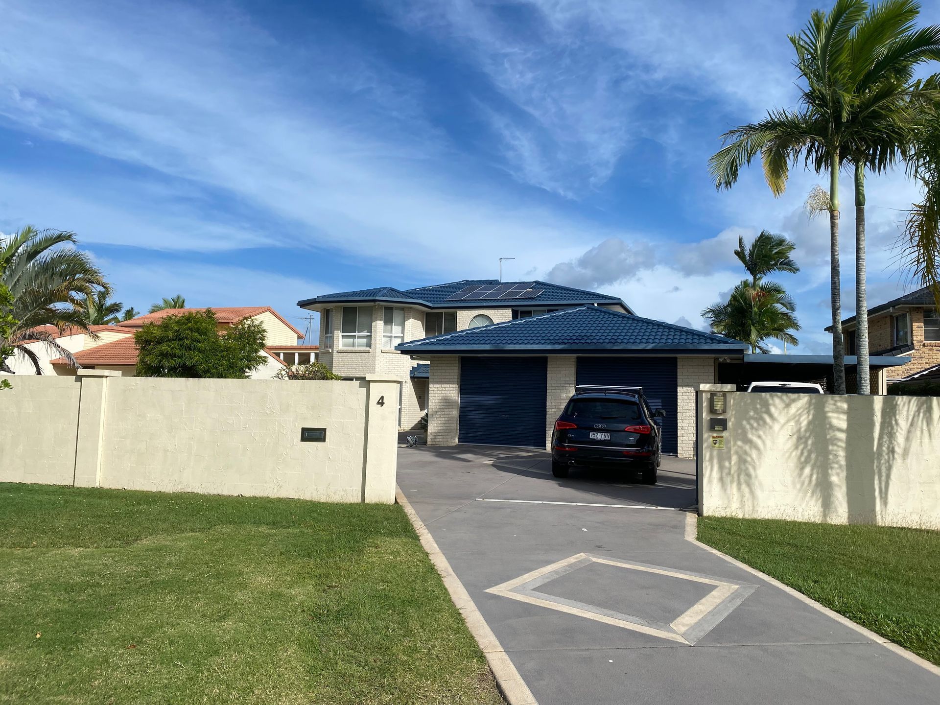 House with blue roof and garage, black car in driveway, sunny day.