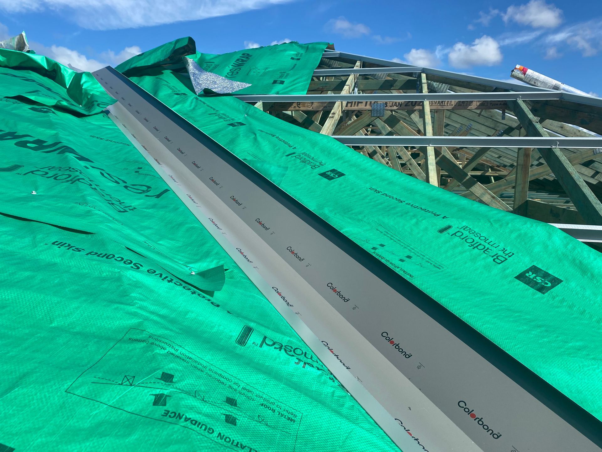 Roof under construction with green waterproof membrane and metal flashing.