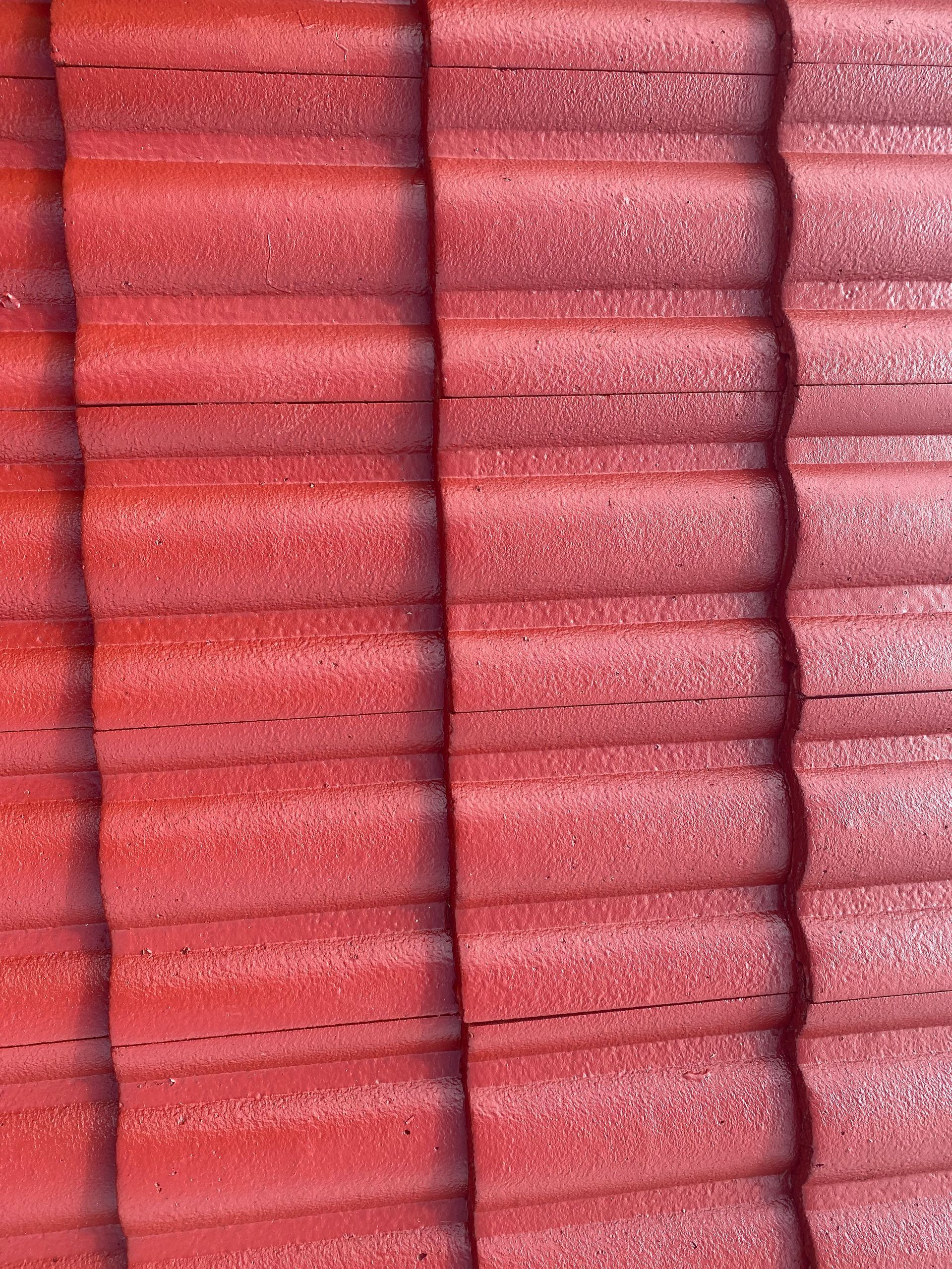 Red, textured roof tiles in a repeating pattern, possibly on a building's roof.
