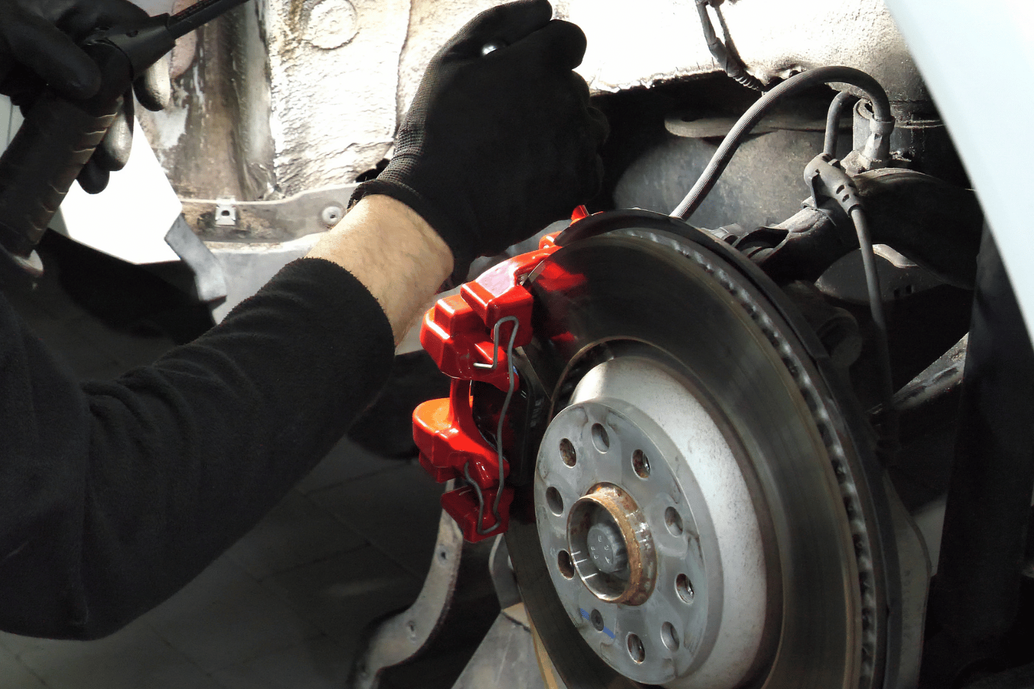 Mechanic repairing a brake caliper on a car in an auto shop