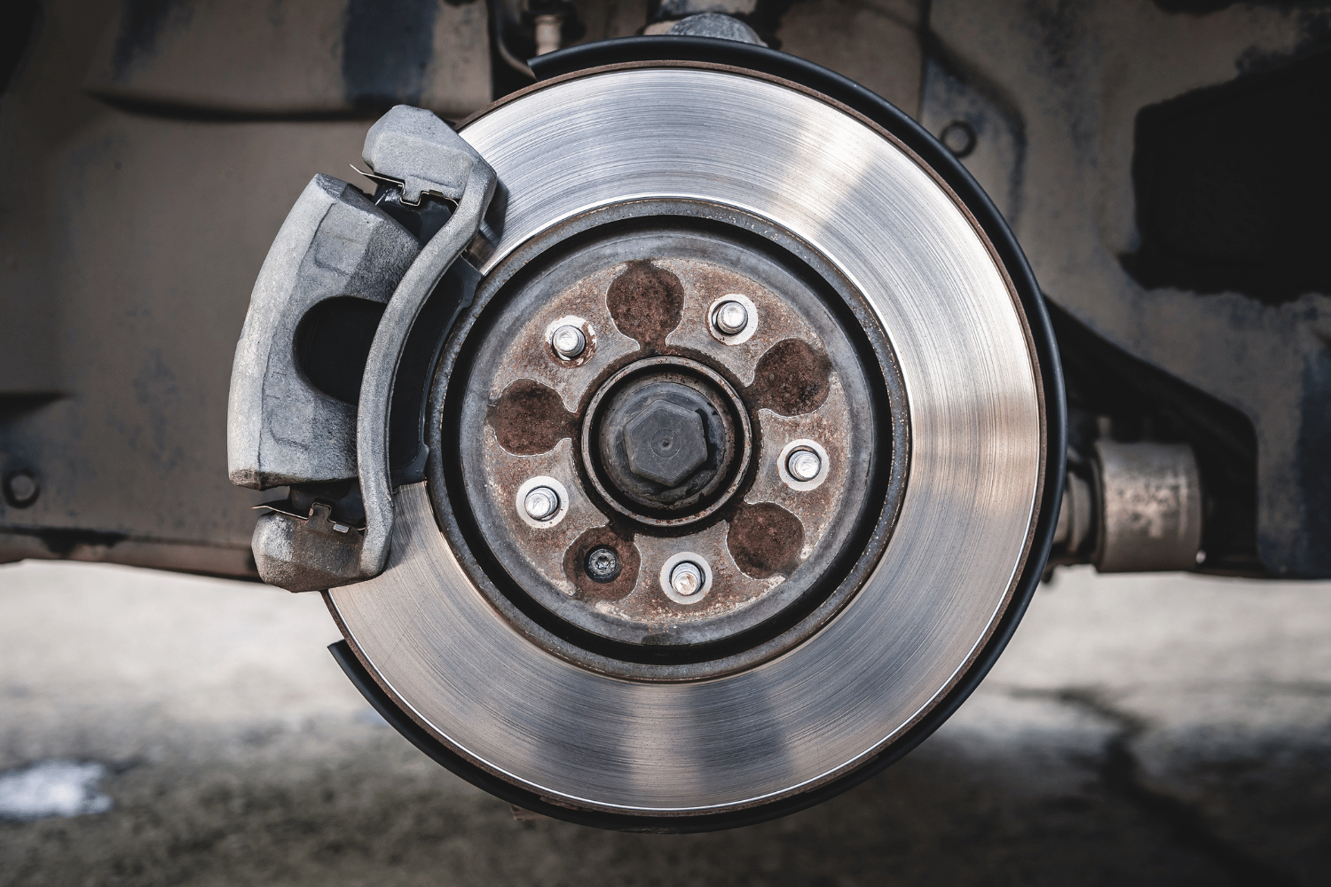 Mechanic inspecting a brake rotor on a lift in an auto repair shop