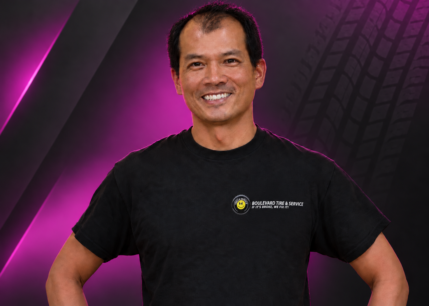 Smiling man in a black T-shirt standing against a purple studio-style background.