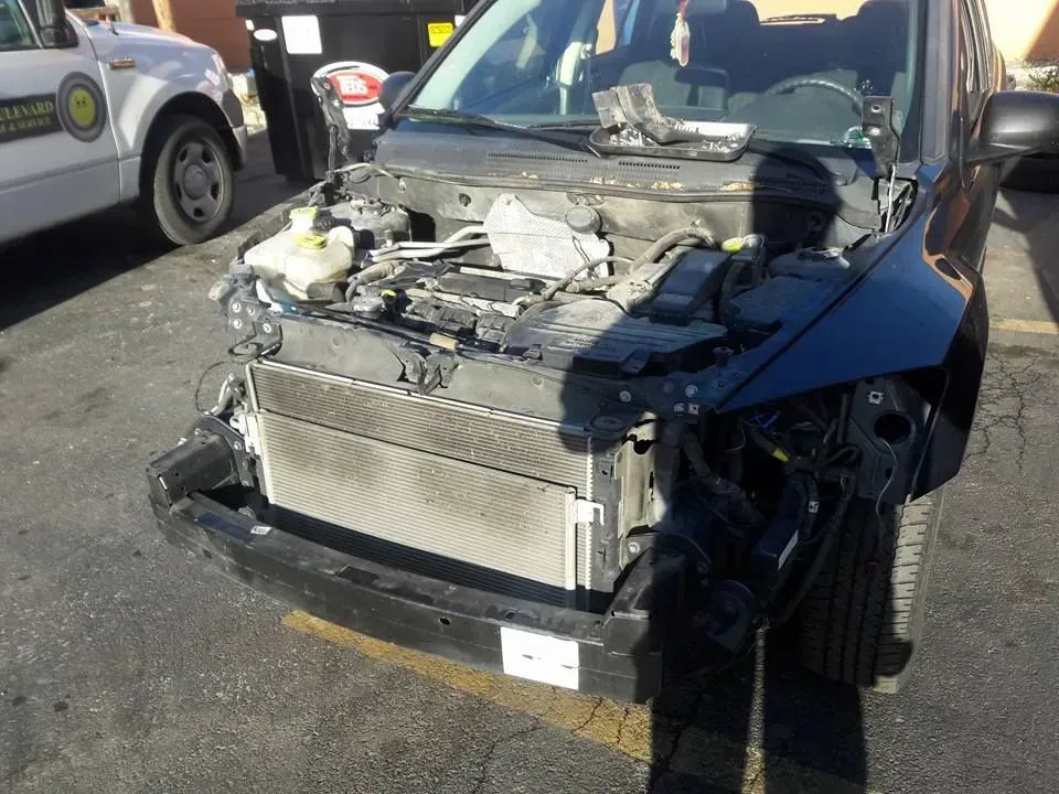 Damaged car with front end removed, exposed engine and radiator, parked in a lot