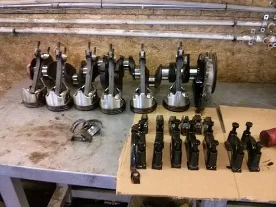 Row of metal engine parts and small black components arranged on a workbench in a workshop