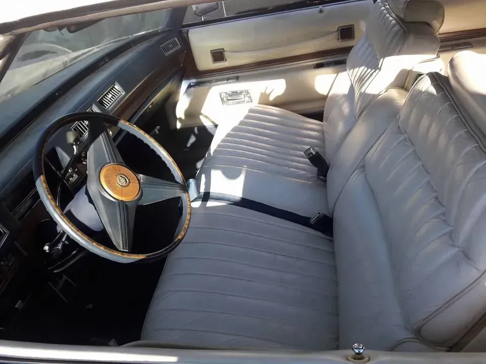 Classic car interior with white bench seat, black dashboard, and steering wheel