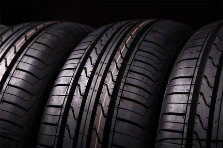 Four black car tires lined up in a row on a dark background