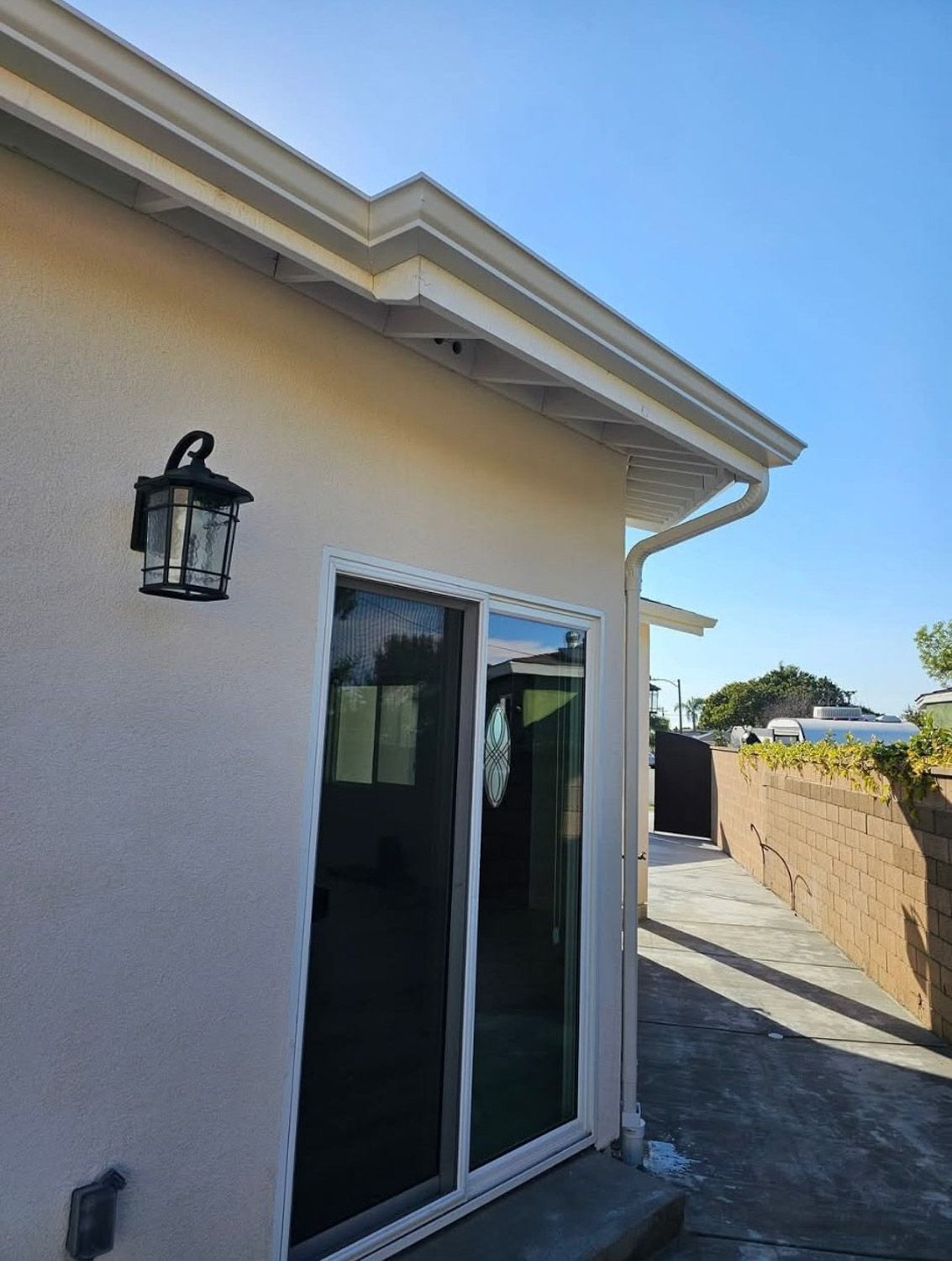 Exterior of a building with a white roof, sliding glass door, and outdoor lamp. New seamless gutters installed by Gutter Specialist in Reno, NV