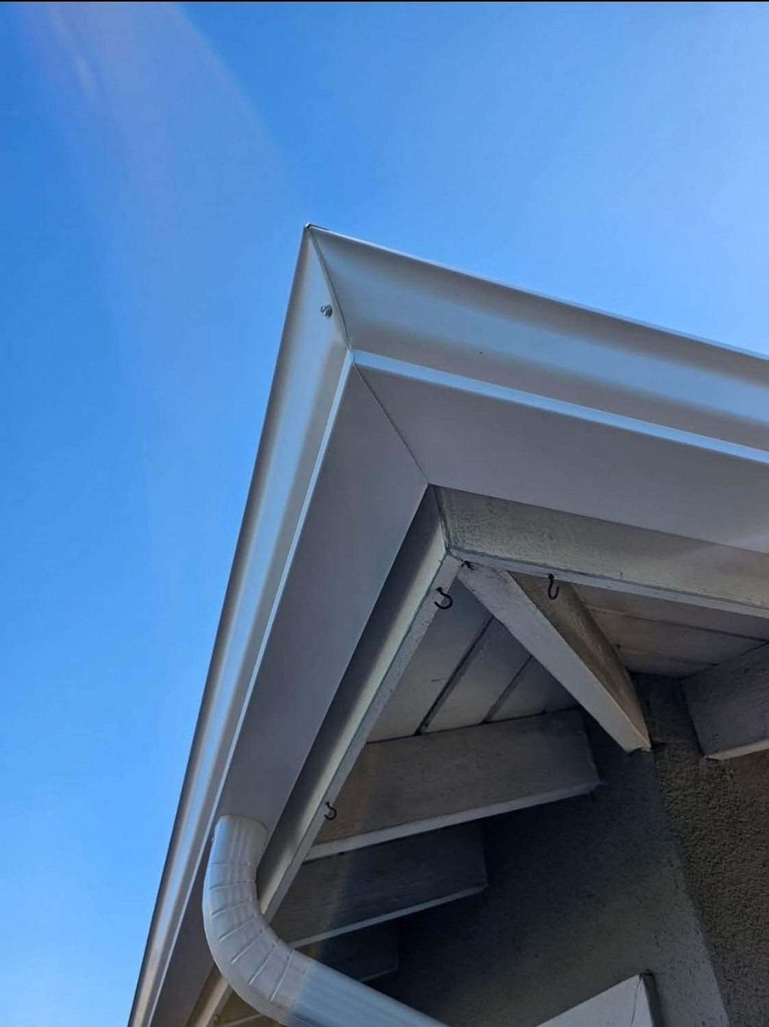 White roof corner with gutter against a blue sky. New seamless gutters installed by Gutter Specialist in Reno, NV