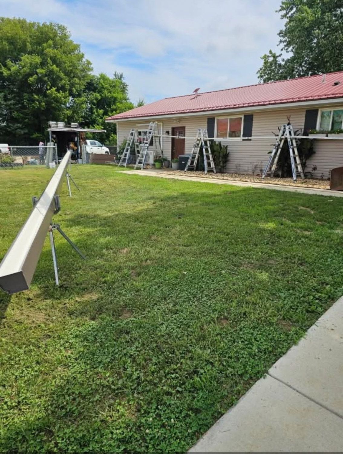 Exterior view of a house with scaffolding and construction materials set up on the lawn.