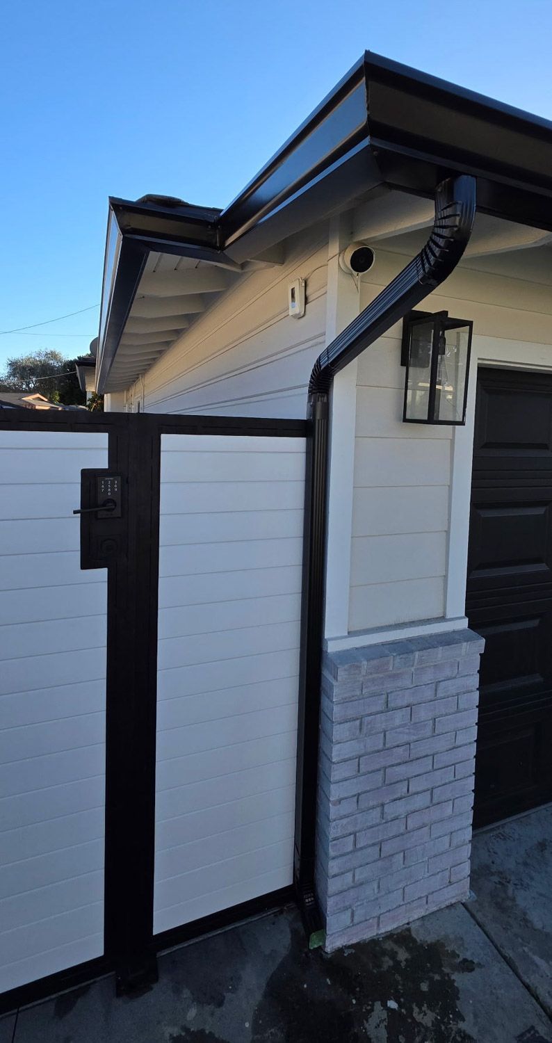 Black and white gate with matching trim, light fixture, brick detail on a building's exterior.