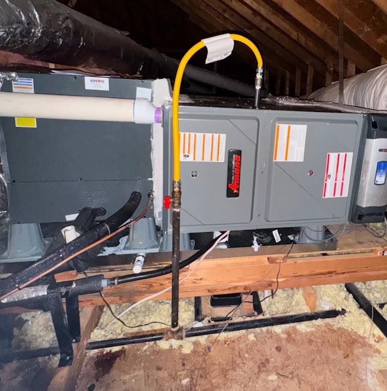 An attic HVAC furnace unit with a connected yellow flexible gas line and shutoff valve.
