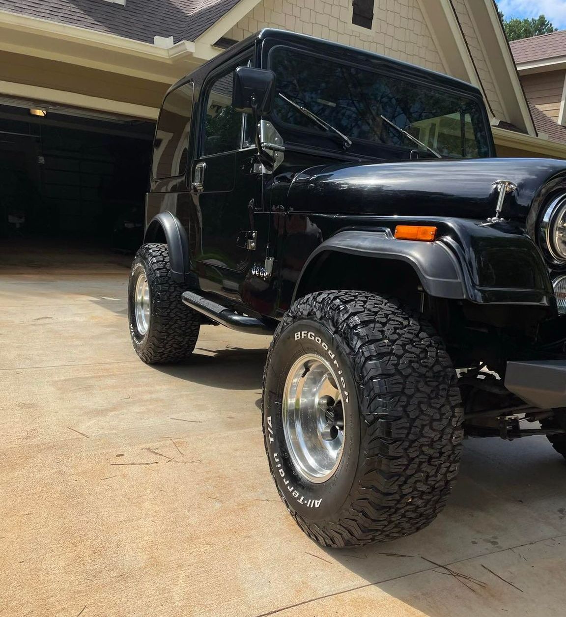 Black Jeep parked in a driveway in front of an open garage