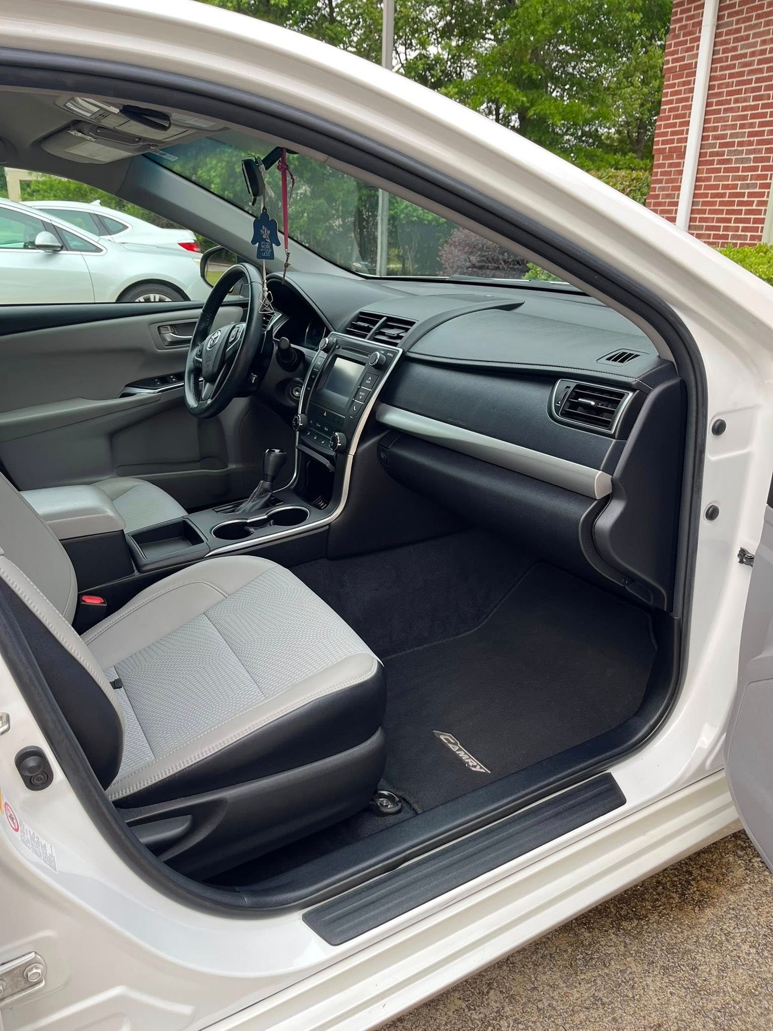 White car interior with front door open, showing dashboard, steering wheel, and front seats