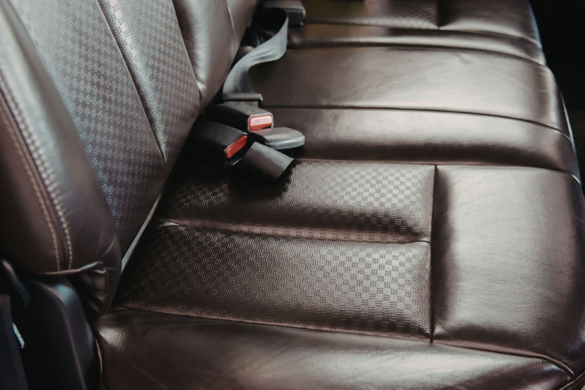 Brown leather car back seat with seatbelt buckles visible