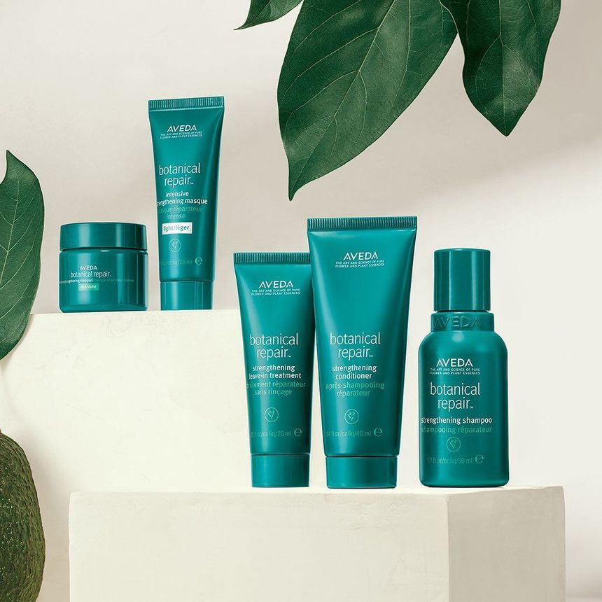 Teal skincare products arranged on a white pedestal with green leaves in the background