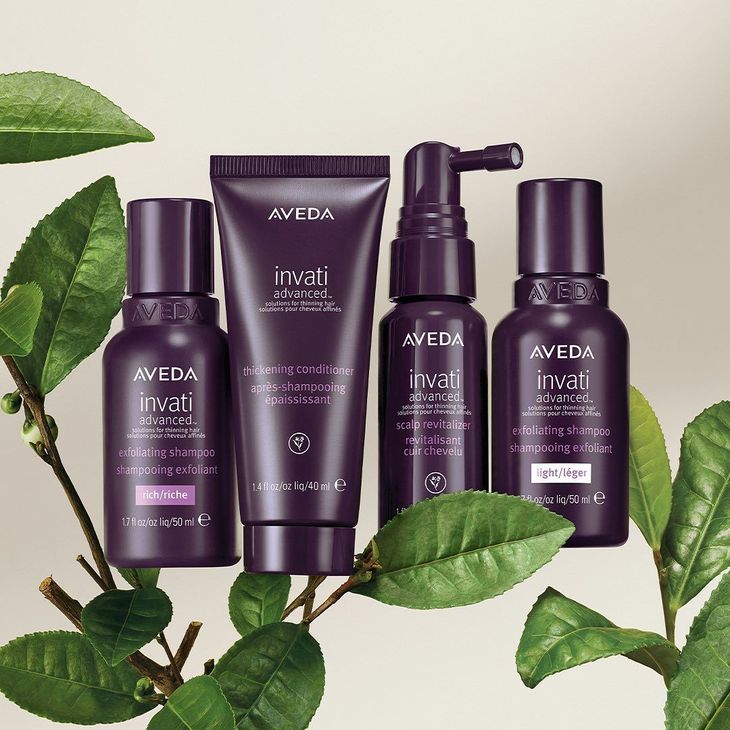 Aveda Invati hair care bottles and tube in purple with green leaves on a light background