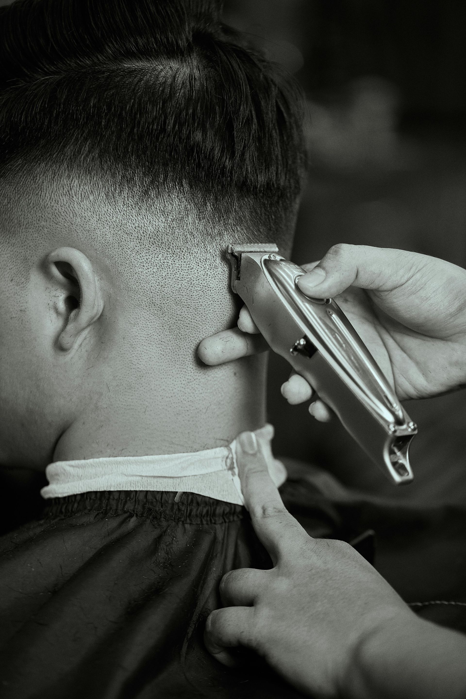 Haircut in progress, with clippers trimming the side of a person's head.