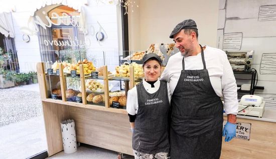 Primo piano di un'esposizione di panini, alcuni con prosciutto, nella vetrina di una panetteria.