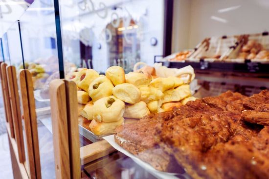 Una vetrina con vari tipi di focacce e pasticcini in un ambiente da panetteria.