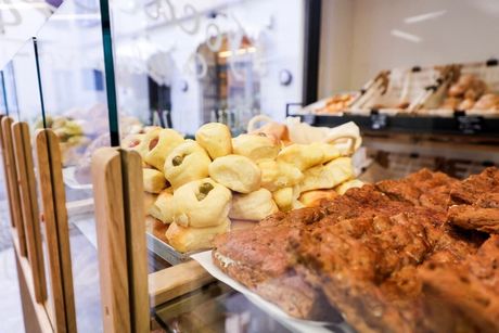 Primo piano di croissant spolverati di polvere bianca, con altri dolci sfocati sullo sfondo.