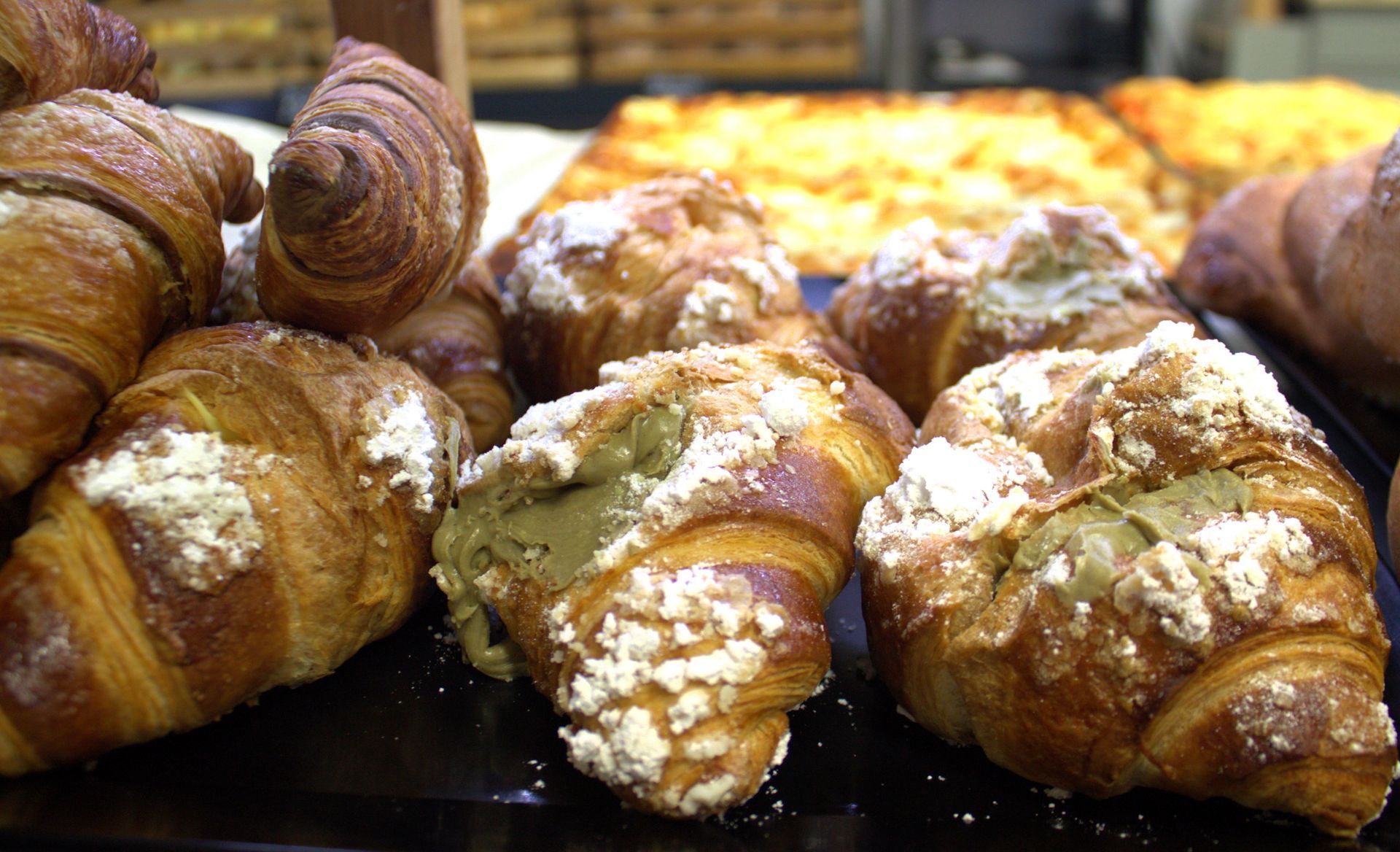 Cornetti dorati ricoperti di zucchero bianco esposti in una panetteria.