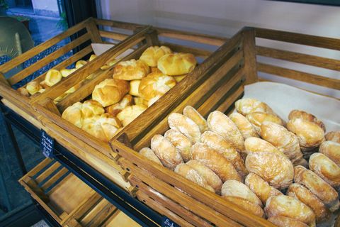 Bancone del panificio con prodotti da forno e due persone sorridenti, una delle quali fa un gesto di pollice in su.
