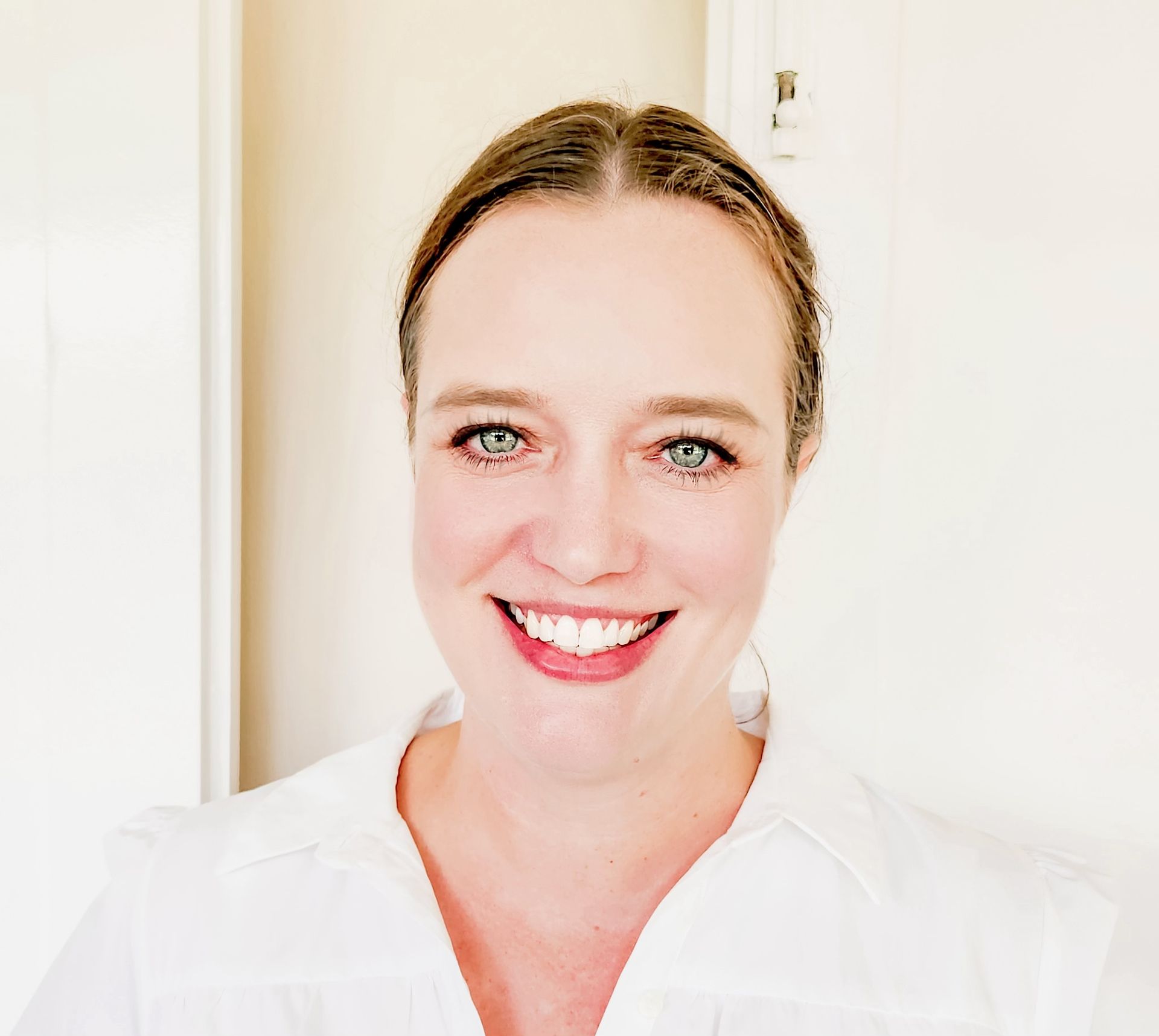 Smiling person in a white shirt against a bright indoor background