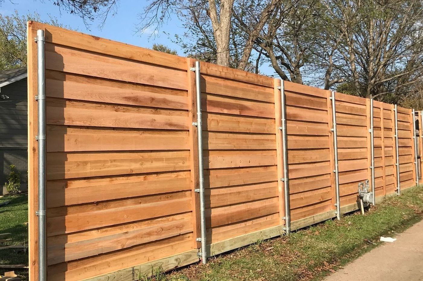 A metal fence surrounds a lush green field.