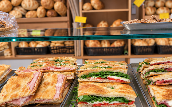 Panini esposti su vassoi in una panetteria o sul bancone di una gastronomia, con pagnotte sullo sfondo