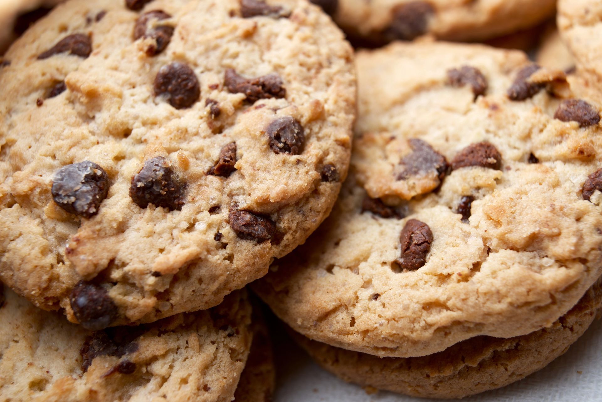 Primo piano di biscotti con gocce di cioccolato impilati su una superficie bianca