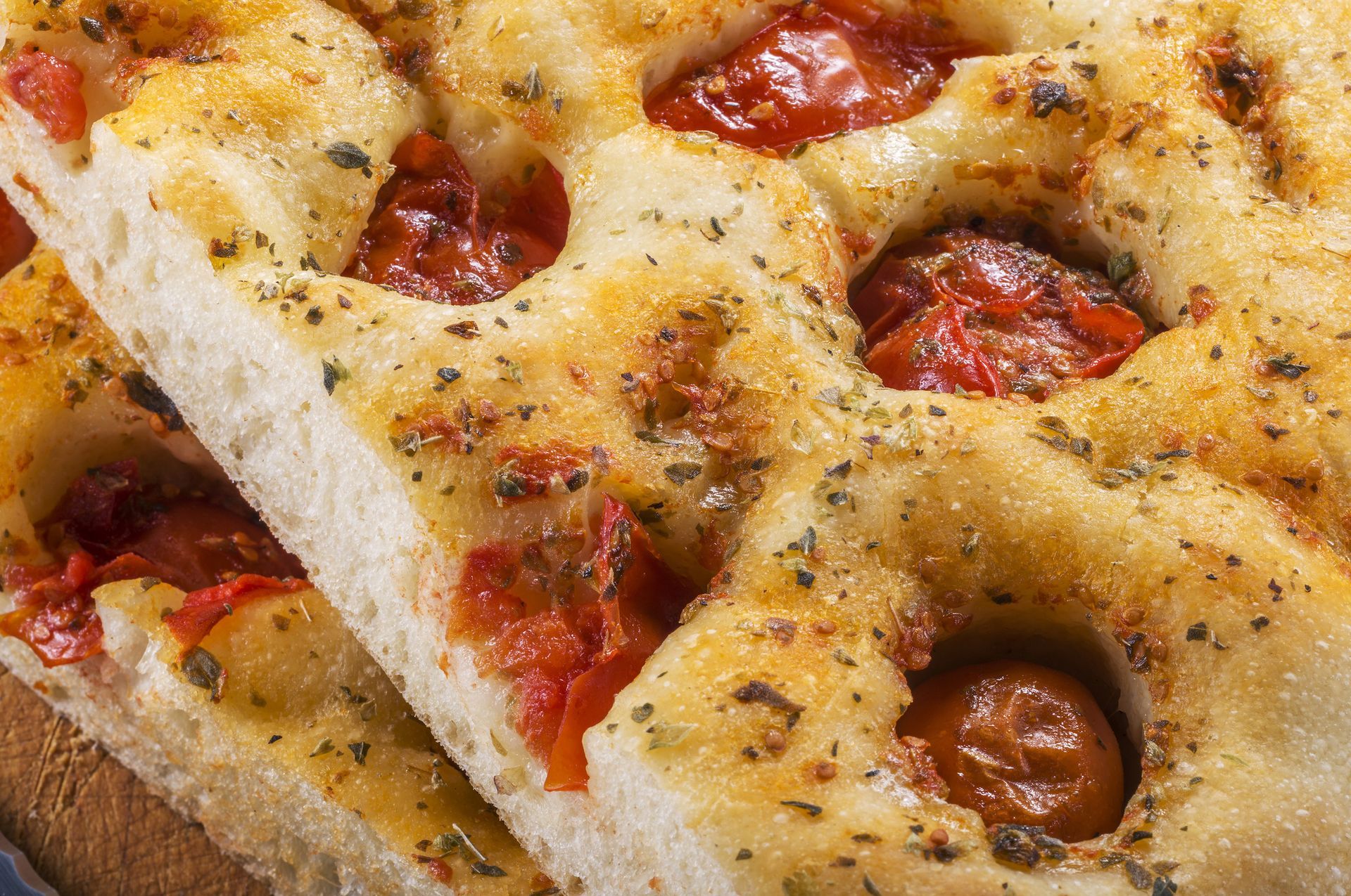 Primo piano di focaccia a fette condita con pomodorini e erbe aromatiche