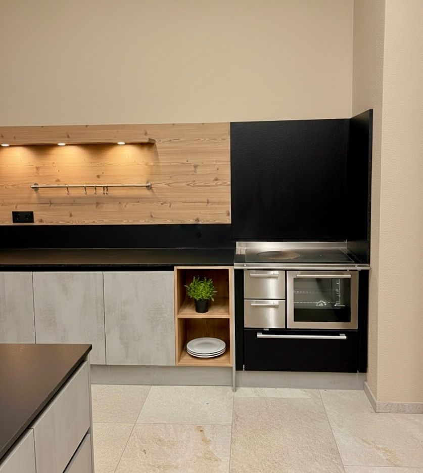 Moderne Küche mit schwarzen Schränken, Holzrückwand, Einbaubackofen und hellem Fliesenboden